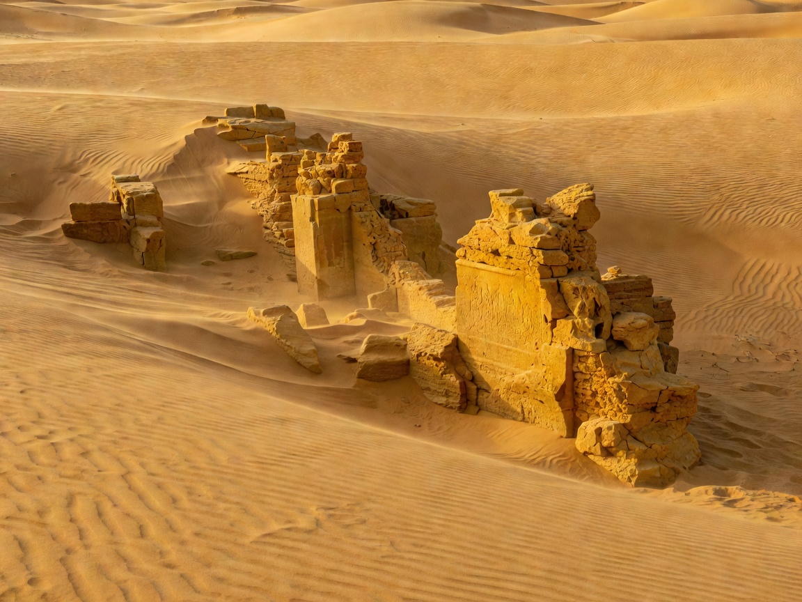 Ruined sandstone brick houses in Kuldhara ghost village under a bright desert sky